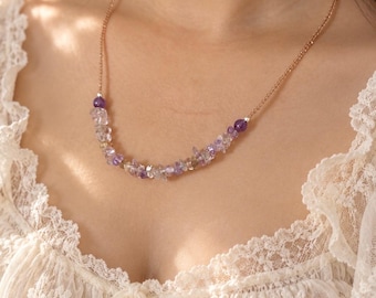 Op de afbeelding: Een delicate ketting met een dunne roségouden ketting, versierd met een centrale opstelling van kleine, onregelmatige, getrommelde amethist- en heldere kwarts-edelsteensplinters, afgewerkt met twee gladde, ronde amethistkralen.