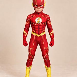 Puede incluir: Un disfraz de superhéroe de cuerpo completo en rojo y amarillo con un emblema de rayo en el pecho, una máscara a juego con detalles de rayos en las orejas y cubrebotas amarillos integrados. El traje incluye una definición muscular impresa.