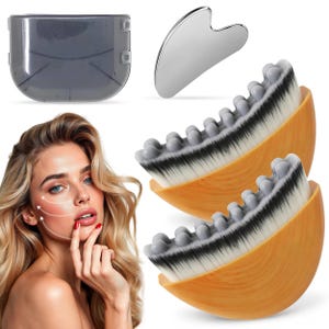 May include: Two oval-shaped facial brushes with light wood-grain handles, dense white and black bristles, and grey massage nodes. Includes a silver heart-shaped gua sha tool and a translucent grey protective case for skincare application.