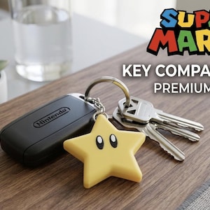 Puede incluir: Un llavero negro de Nintendo y un llavero amarillo en forma de estrella con una cara sonriente están unidos a un llavero con llaves. La imagen incluye el logotipo de Super Mario y el texto "KEY COMPANION PREMIUM PETG".