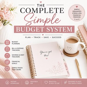 Könnte beinhalten: Ein rosa Budgetplaner mit goldener Spiralbindung, mit dem Text "You've got this!" und floralen Akzenten. Der Planer ist geöffnet, mit Registerkarten für Budget, Track, Save und Plan. Eine Kaffeetasse und ein goldener Stift sind ebenfalls zu sehen.