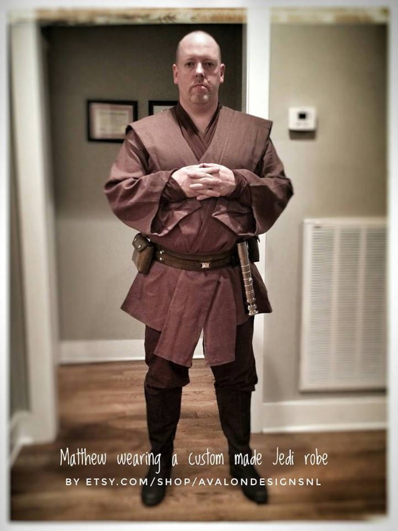 Puede incluir: Una persona vistiendo una t&uacute;nica Jedi marr&oacute;n con un cintur&oacute;n marr&oacute;n y un sable de luz. El texto "Matthew wearing a custom made Jedi robe BY ETSY.COM/SHOP/AVALONDESIGNSNL" est&aacute; en la parte inferior de la imagen.