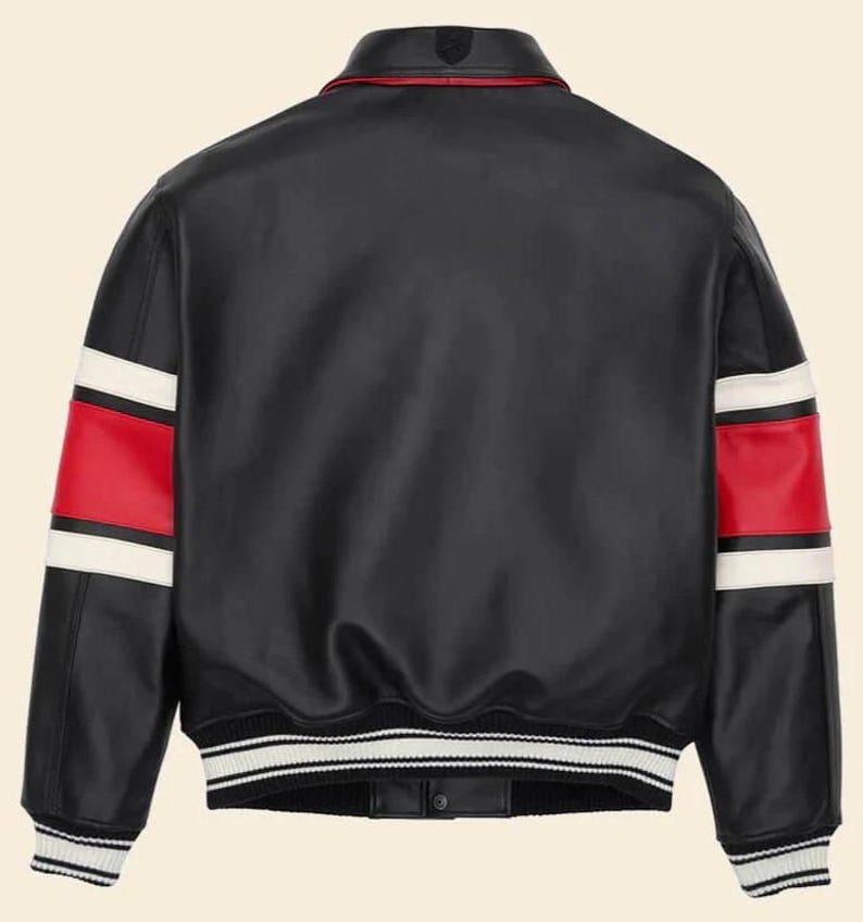 May include: A black leather varsity jacket featuring a fold-down collar, long sleeves with horizontal red and white stripes, and a ribbed hem with black and white stripes. The jacket has a smooth finish and a button-down front closure at the bottom.