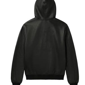 K&ouml;nnte beinhalten: Eine schwarze Lederjacke mit Kapuze, langen &Auml;rmeln sowie gerippten Strickb&uuml;ndchen an &Auml;rmeln und Saum. Die Jacke ist von der R&uuml;ckseite zu sehen und zeigt eine glatte, durchgehend schwarze Oberfl&auml;che &uuml;ber das gesamte Kleidungsst&uuml;ck hinweg.