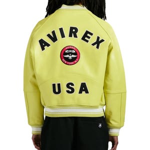 May include: A lime green varsity jacket featuring the text AVIREX in black letters across the upper back, a circular red and black patch with an anchor and wings logo, and the text USA in black letters above the white and lime green striped hem.