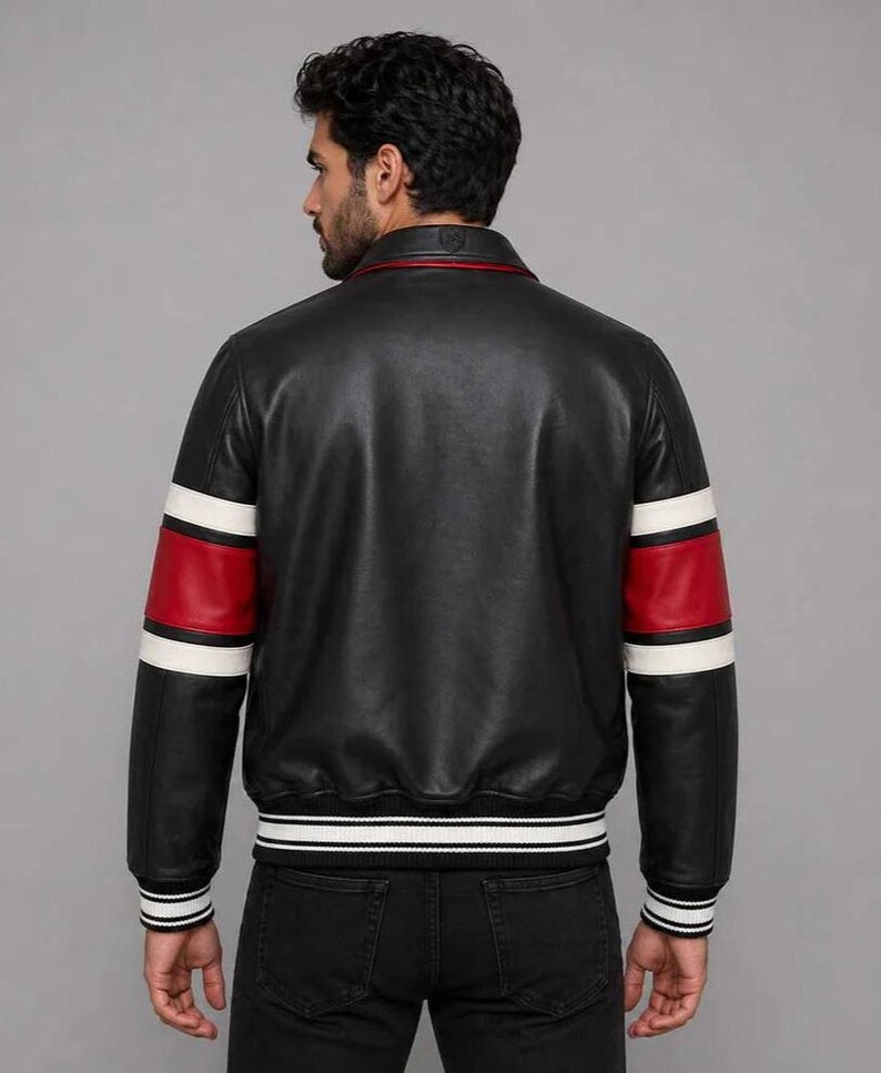 May include: A black leather jacket featuring a classic collar and long sleeves with prominent red and white horizontal stripes. The garment includes a ribbed hem and ribbed cuffs with white and black stripes, providing a structured fit.