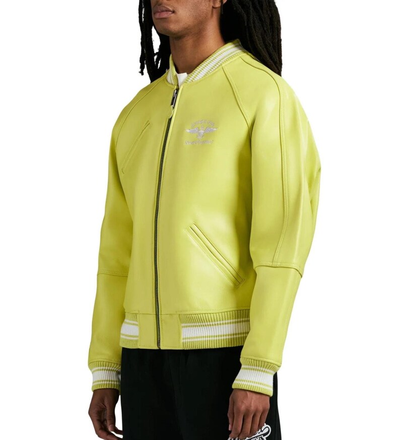 May include: A lime green bomber jacket featuring a front zipper closure, ribbed collar, and ribbed cuffs with white stripes. The jacket includes two slanted side pockets and a small embroidered emblem on the upper left chest area.