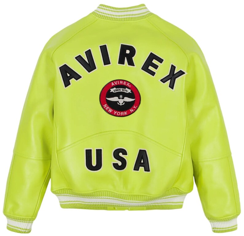 May include: A neon yellow bomber jacket featuring the black text AVIREX arched above a circular red, white, and black patch with an anchor emblem, and the black text USA below. The jacket has white and neon yellow striped ribbed trim at the collar.