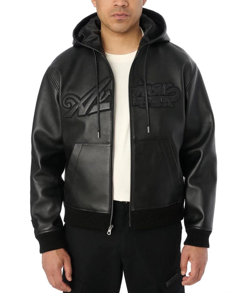 K&ouml;nnte beinhalten: Eine schwarze Lederjacke mit Kapuze, durchgehendem Frontrei&szlig;verschluss, gerippten B&uuml;ndchen und Saum sowie zwei Vordertaschen. Auf der Brust befindet sich eine gepr&auml;gte, tonale Schrift. Getragen &uuml;ber einem wei&szlig;en Shirt und einer schwarzen Cargohose.