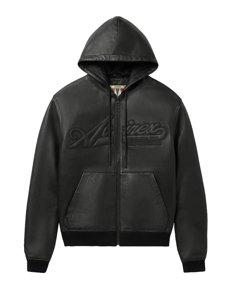 K&ouml;nnte beinhalten: Eine schwarze Lederjacke mit Kapuze, durchgehendem Frontrei&szlig;verschluss, langen &Auml;rmeln mit gerippten B&uuml;ndchen und einem gerippten Saum. Auf der Brust befindet sich der gepr&auml;gte Schriftzug "Avirex". Die Jacke verf&uuml;gt &uuml;ber eine K&auml;ngurutasche.