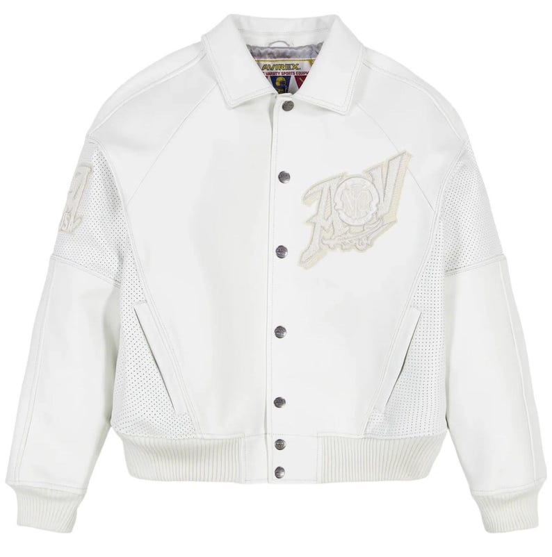 May include: A white varsity jacket featuring a classic collar, snap-button front closure, and ribbed cuffs and hem. The jacket includes perforated leather panels on the sides and sleeves, with an embroidered Avirex logo patch on the chest.