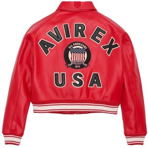May include: A bright red varsity jacket featuring the text AVIREX in black letters arched across the upper back. Below this, a circular patch displays the text ALL AMERICANS ESTABLISHED 1975 with a US flag. The word USA is printed in black below.