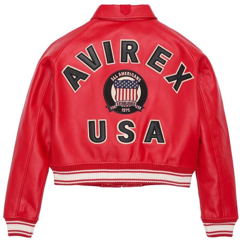 May include: A bright red varsity jacket featuring the text AVIREX in black letters arched across the upper back. Below this, a circular patch displays the text ALL AMERICANS ESTABLISHED 1975 with a US flag. The word USA is printed in black below.