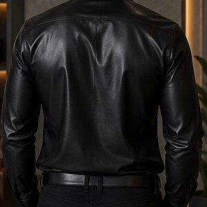 Puede incluir: Una camisa negra de manga larga con un acabado liso y brillante y cuello cl&aacute;sico. La camisa presenta una parte delantera abotonada, un canes&uacute; trasero y mangas largas con pu&ntilde;os abotonados, metida dentro de unos pantalones negros con cintur&oacute;n.