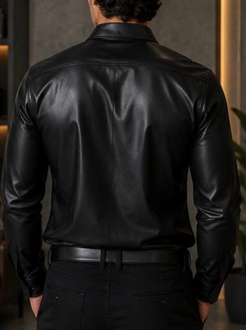 Puede incluir: Una camisa negra de manga larga con un acabado liso y brillante y cuello cl&aacute;sico. La camisa presenta una parte delantera abotonada, un canes&uacute; trasero y mangas largas con pu&ntilde;os abotonados, metida dentro de unos pantalones negros con cintur&oacute;n.