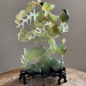 Escultura china antigua tallada en piedra de jade con forma de árbol y pájaros, con base de madera.