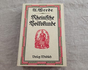Pode incluir: Um livro de capa dura intitulado Rheinische Volkskunde de A. Wrede, publicado pela Verlag Weidlich. A capa em tom off-white apresenta uma ilustração vermelha de uma pessoa em trajes tradicionais, emoldurada por uma borda geométrica vermelha e verde.