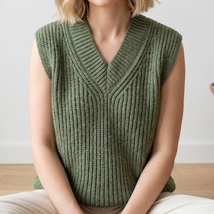 May include: A green knitted vest with a V-neck. The sleeveless top is made of a ribbed knit fabric. The vest is a solid olive green colour.