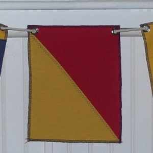 May include: A string of nautical signal flags in blue, yellow, and red, hanging from a white rope. The flags have various patterns, including solid colors, stripes, and diagonal divisions. The word "DOG" is printed on the bottom right corner.