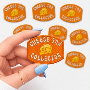 May include: Orange embroidered patch with the text "CHEESE TAX COLLECTOR" and a yellow cheese graphic. Several patches are visible, with one held by a hand. The patches are rectangular with rounded corners.