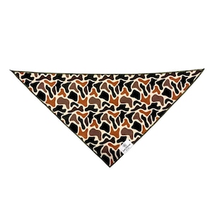 Puede incluir: Un pa&ntilde;uelo triangular con un estampado de camuflaje en tonos marrones, negros y crema. El pa&ntilde;uelo tiene un borde verde oscuro y una peque&ntilde;a etiqueta blanca con texto. La tela est&aacute; doblada en forma de tri&aacute;ngulo.