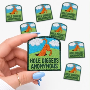 May include: Embroidered patch with a green border, featuring a cartoon dog digging a hole. The patch has a blue sky with white clouds and the text "HOLE DIGGERS ANONYMOUS" in green. Several patches are visible.