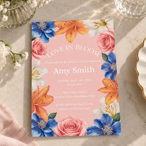 Può includere: Un invito rettangolare per addio al nubilato con sfondo rosa tenue, caratterizzato da un bordo floreale di fiori blu, arancioni, bianchi e rosa. Il testo recita: Love in Bloom, Please join us for a bridal shower honoring Amy Smith, Saturday, April 10th, 2027 at 1:00 PM, The Garden House, 123 Rose Lane, Anywhere, Ohio, Kindly RSVP by March 20th, Emma at (555) 123-4567.