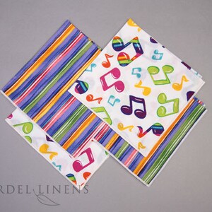 May include: Three fabric napkins with colorful designs. One napkin has a rainbow stripe pattern, another has a white background with colorful musical notes, and the third has a white background with colorful musical notes and a rainbow stripe border.
