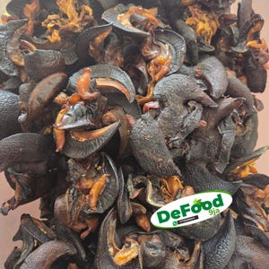 May include: A close-up shot of a pile of dark brown, dried food items with a distinctive, layered texture. The food has a leathery appearance with some areas showing a lighter, orange-brown colour. The image includes a logo that says "DeFood 9ja".