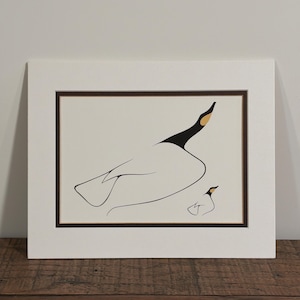 May include: A matted art print featuring a minimalist line drawing of a large goose and a smaller gosling. The birds are rendered in black ink with gold-colored accents on their heads, set against a cream background within a dark brown border.