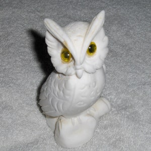 Puede incluir: Figurita de b&uacute;ho de cer&aacute;mica blanca con ojos amarillos. El b&uacute;ho est&aacute; posado sobre una base y tiene plumas detalladas.