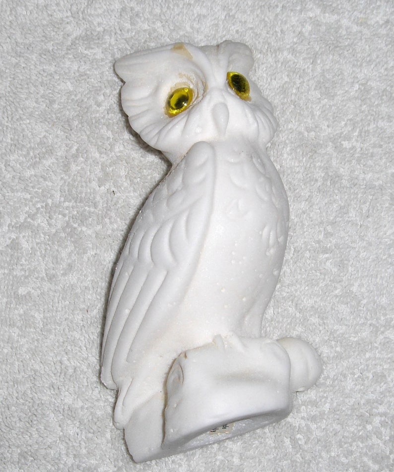 Puede incluir: Figurita de b&uacute;ho de cer&aacute;mica blanca con ojos de vidrio amarillo. El b&uacute;ho est&aacute; posado sobre una base y tiene plumas detalladas.