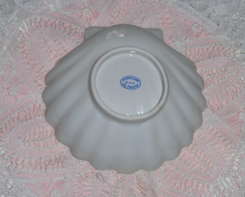 K&ouml;nnte beinhalten: Wei&szlig;e Porzellan-Muschel-Schale mit einem blauen und wei&szlig;en Stempel auf der Unterseite, der "Porcelaine P.F.C. De France" lautet.
