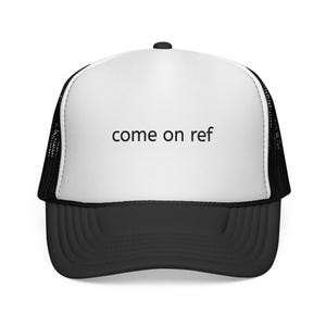 May include: A black and white trucker hat with the text "come on ref" in black. The hat has a white front panel with the text, a black brim, and a black mesh back.
