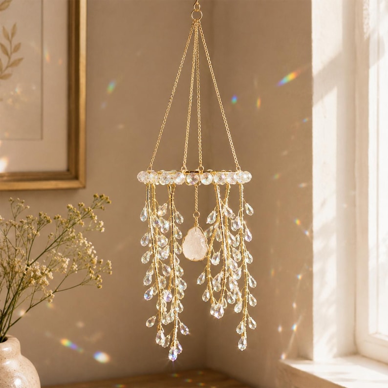 May include: A hanging mobile featuring a circular gold frame adorned with clear crystal beads. Multiple gold wire strands dangle from the frame, each decorated with teardrop-shaped clear crystals. A single raw white stone hangs in the center.