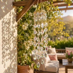 May include: A hanging decorative ornament featuring a gold-toned metal frame and multiple strands of clear, faceted glass crystals. The crystals are arranged in circular and teardrop shapes, suspended by thin gold chains from a central ring.