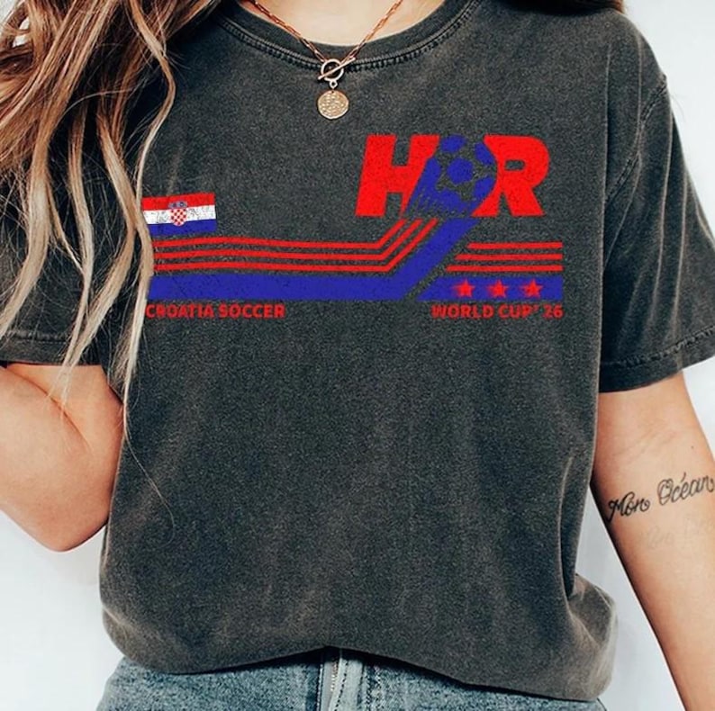 May include: Dark gray t-shirt with a Croatia soccer design. The design includes the letters "H" and "R" in red, a Croatian flag, and the text "Croatia Soccer World Cup '16". The shirt has a vintage, worn look.
