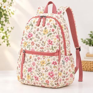 May include: A backpack featuring a cream-coloured base with a repeating floral pattern of pink and yellow flowers and green leaves. The bag includes pink zips, a front zipped pocket, two side pockets, and adjustable pink shoulder straps.