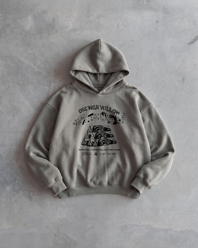 May include: A gray hoodie with a drawstring hood and a kangaroo pocket. The front features a graphic with the text "ONE WISH WILLOW" and an illustration. The hoodie is made of a soft material.