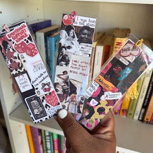 May include: Three rectangular clear bookmarks featuring collage-style designs with various printed text and graphics. The left bookmark displays "Emotional Support Kindle" and "Book Lover" text. The center features black and white imagery with "I was born to tell stories" text. The right bookmark includes "Always" and "Romance Reader" text.