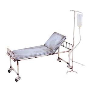 Puede incluir: Una cama de hospital de metal blanco en miniatura, desgastada, con un colchón a rayas y un soporte de goteo a juego. La cama tiene ruedas y cabecero. El soporte de goteo contiene una bolsa de líquido transparente y tubos.
