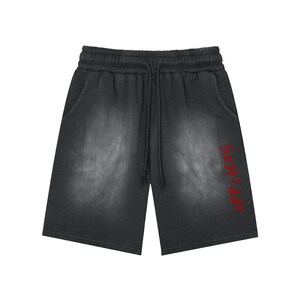 Puede incluir: Pantalones cortos negros con un efecto gris deslavado en los paneles frontales. La prenda incluye una cintura elástica con cordón y el texto rojo "APPLAGOS" impreso verticalmente a lo largo de la parte inferior derecha de la pierna.
