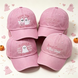 May include: Four light pink baseball caps with embroidered designs. One features a ghost and bee with 'SAVE THE BOO BEES', another says 'CHECK YOUR BOO BEES', one reads 'GHOULS JUST WANNA WEAR PINK IN OCTOBER', and the last says 'Breast Cancer is Boo Sheet'.