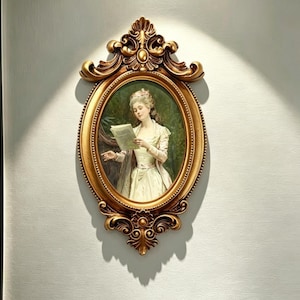 Könnte beinhalten: Ein ovales Wandporträt mit einem Gemälde einer Figur in einem hellen Kleid, die ein Buch liest, eingefasst in einen verzierten, goldfarbenen Rahmen mit komplexen Schnörkeln und floralen Schnitzereien an den oberen und unteren Rändern.