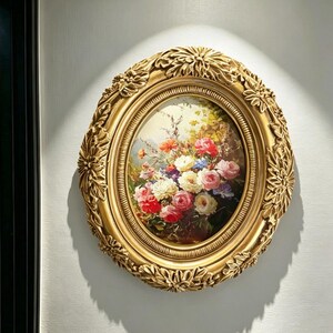 Könnte beinhalten: Ein ovales Wandgemälde mit einem lebendigen Blumenarrangement aus Rosen in den Farben Rot, Rosa, Weiß und Gelb. Das Kunstwerk ist in einem verzierten, goldfarbenen Rahmen mit detaillierten Blatt- und Blumenschnitzereien eingefasst.