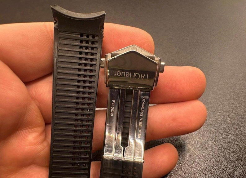 Pu&ograve; includere: Cinturino per orologio in gomma nera con chiusura in acciaio inossidabile. La chiusura &egrave; contrassegnata con "TAGHeuer" e "STAINLESS STEEL F 95". Il cinturino ha un design a coste ed &egrave; contrassegnato "FC 5030".
