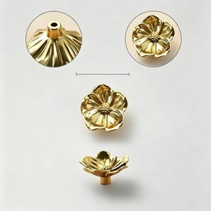 May include: Gold-colored flower-shaped cabinet knobs. The knobs have a detailed petal design and a central, textured core. The hardware is shown in multiple views, including a close-up of the knob's base and a top-down view.