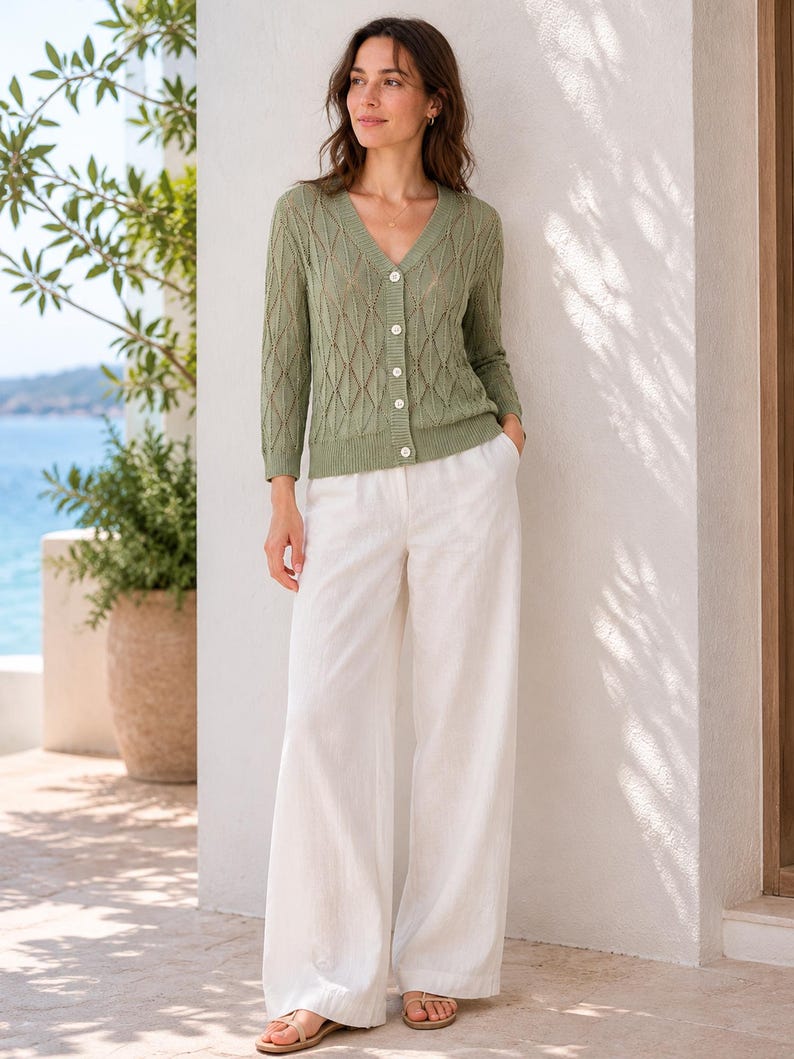 May include: A sage green V-neck cardigan featuring a diamond-patterned knit texture, long sleeves, and a front button closure, paired with wide-leg white trousers. The cardigan has ribbed cuffs and a ribbed hem, while the trousers are full-length.