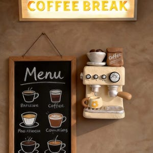 Puede incluir: Decoración mural con temática de café que presenta un letrero luminoso "COFFEE BREAK". Debajo, una pizarra con un menú de tipos de café y una máquina de espresso en miniatura con una taza. La decoración es en tonos beige y marrón.