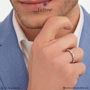 Op de afbeelding: Een zilveren ring met meerdere kleine, rechthoekig geslepen edelstenen. De ring zit om de vinger van een persoon. De afbeelding bevat de tekst "Eclisse Jewels" en een websiteadres.